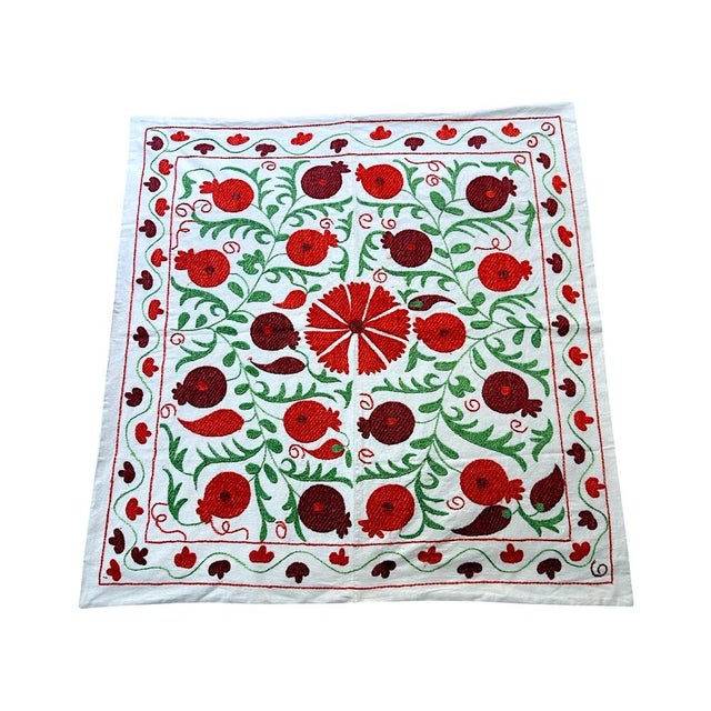 Bring a touch of exotic elegance to your dining table with this hand-embroidered Suzani tablecloth. Featuring a...