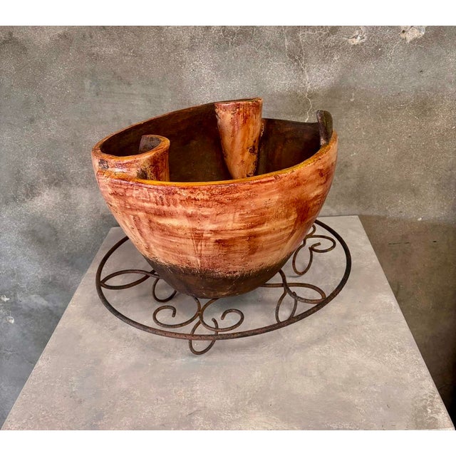 Unique hand-carved wooden vessel with an abstract, ribbon-like rim design and a rich, earthy finish. The deep reddish-...