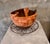 Unique hand-carved wooden vessel with an abstract, ribbon-like rim design and a rich, earthy finish. The deep reddish-...