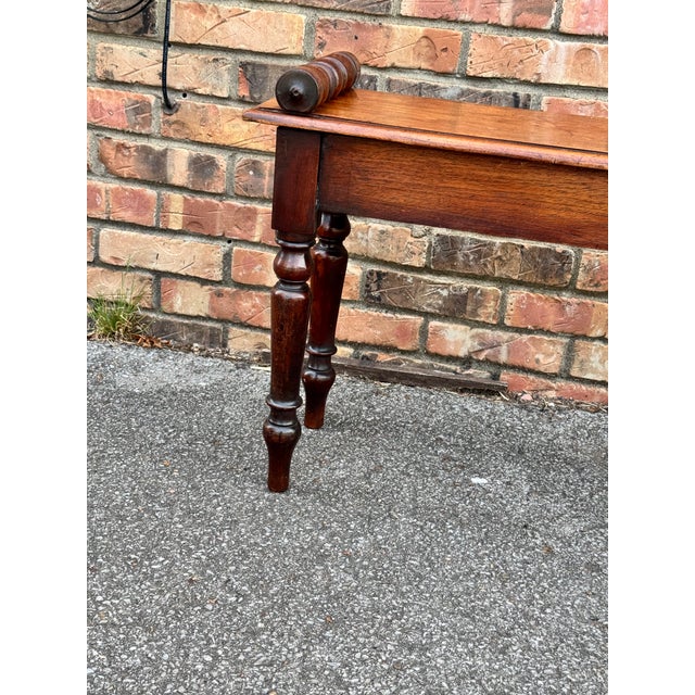 This is an 19th century wood hall bench in English with delicately hand carved rolled arms. Its solid construction, peg...