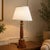 Neoclassical column table lamp dating to the 1950s, made from turned hardwood with a warm reddish-brown finish and visible...
