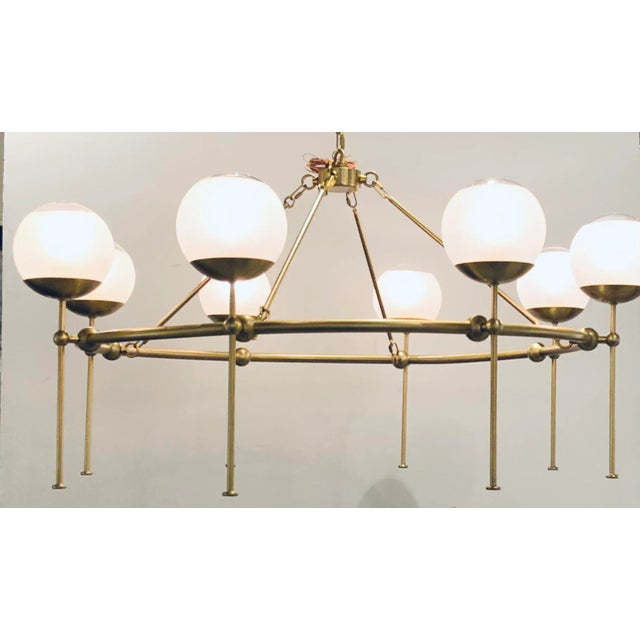Original Retail $4240, stylish Currey & Co. Modern Satin Brass Finished Montview Chandelier, eight frosted glass globes,...