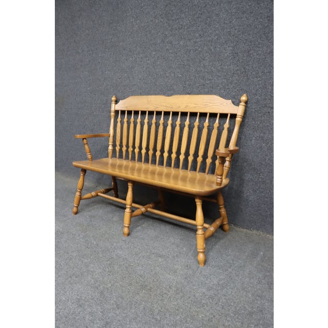 Solid oak bench with a spindle back, shaped crest rail, and turned legs. Features a warm, natural oak finish and gently...