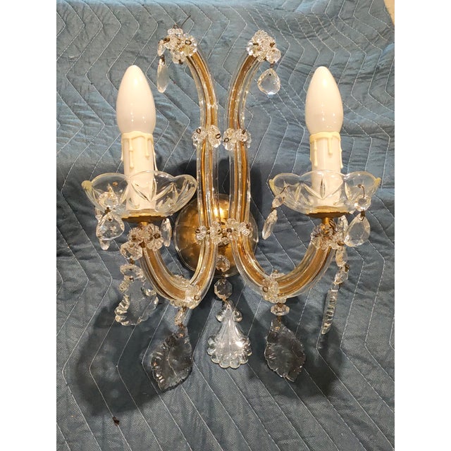 Circa 1900. Elegant pair of French Rococo Revival wall sconces featuring gracefully curved glass arms with warm golden...