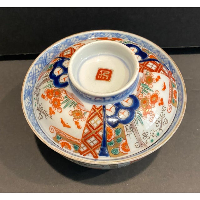 Antique Japanese Imari decorated tea bowl. Orange, gold, blue and maroon on the outside, with blue and white decoration on...