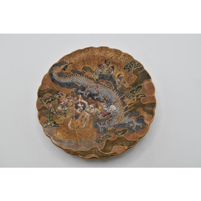 This is a stunning Japanese Satsuma dish. It is from the Meiji period (1868–1912). It depicts monks and a large dragon....