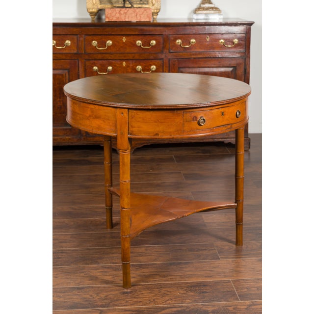 An English pine center table from the mid-19th century, with partitioned drawer, faux bamboo legs and triangular shelf....