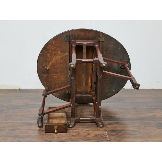 Compact and versatile, this 19th-century English oak drop-leaf table offers both practicality and timeless character....