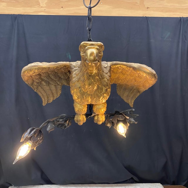 Stunning French carved gilt wood chandelier centered by a finely sculpted eagle with outstretched wings, perched above a...