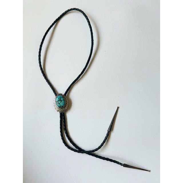 Vintage Navajo bolo tie hand crafted from silver. Features scalloped and stamped edges with a large kingman turquoise...
