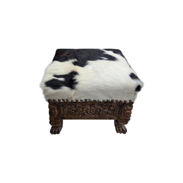The Oriental carved footstool with cow leather is a fully assembled, antique, and handmade furniture piece. This white...