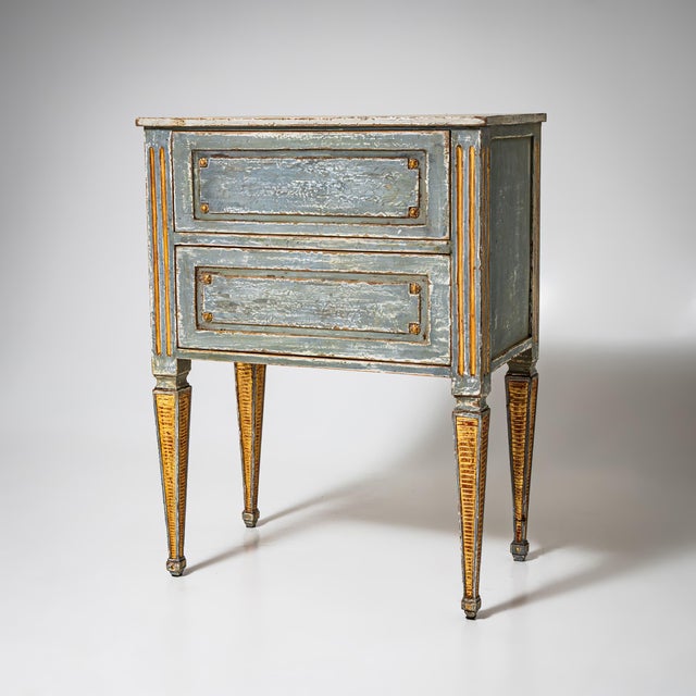 Hand-painted Louis XVI chest of drawers with two drawers and tapered legs. Finished in light blue with gilded accents. The...