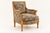 A sculptural armchair featuring a richly carved wood frame and geometric patterned upholstery in muted blue and ochre...