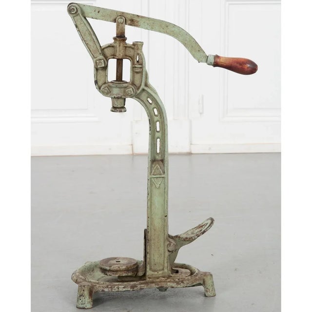 A cast iron wine corker from 19th century France, painted a pastel green like verdigris and using a turned wood handle to...