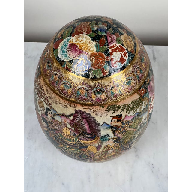 This impressive antique porcelain egg is richly decorated in the Satsuma style, featuring finely detailed figures, samurai...