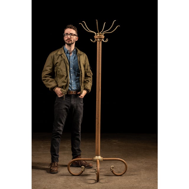 Antique floor-length coat rack with a painted exterior. This piece features six double-sided brass hooks. It sits on a...