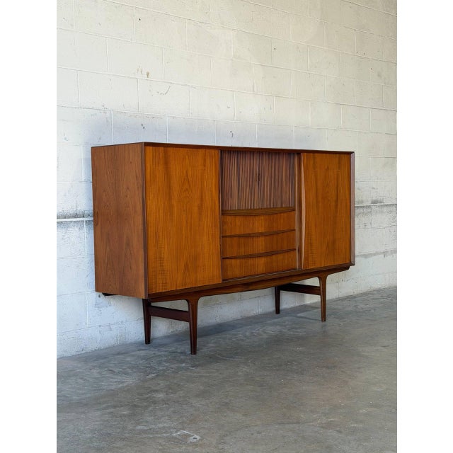 This substantial sideboard features a broad profile with smooth sliding doors. The center reveals three drawers beneath a...