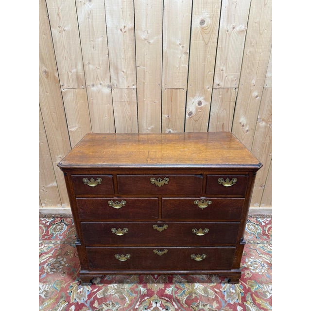 An 18th-century English chest of drawers in solid oak, Georgian style, circa 1740-1780. It features a configuration of...