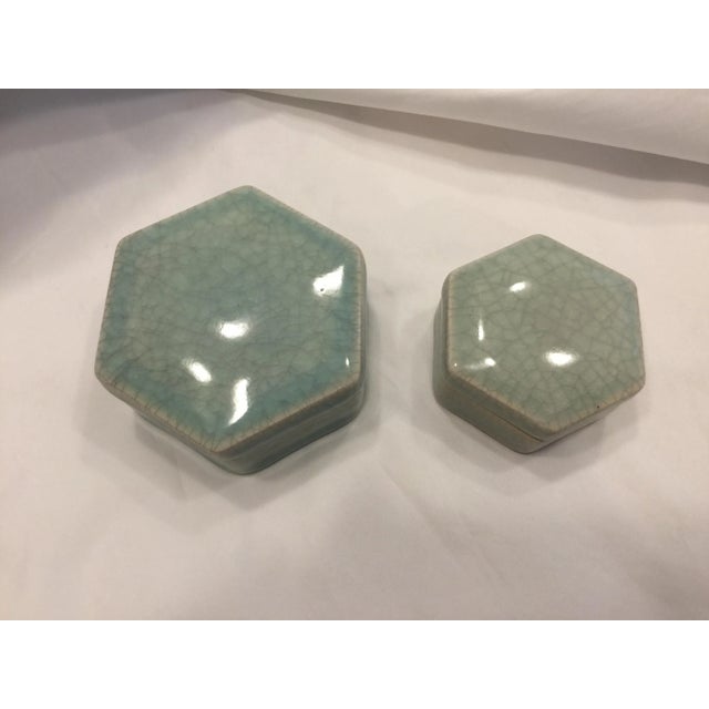A pair of handmade soft green celadon porcelain boxes with a rich luster and overall crackle glaze. Smaller box is 2.75”...