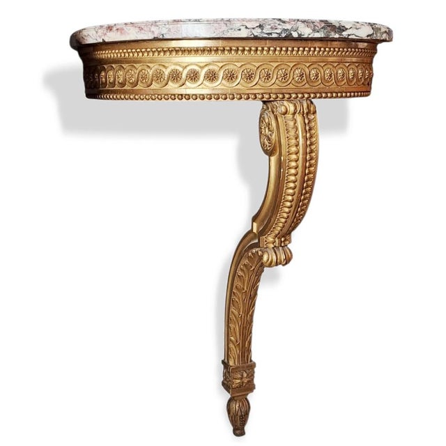 A refined pair of Louis XVI-style wall console tables, characterized by an elegant architectural structure and rich...