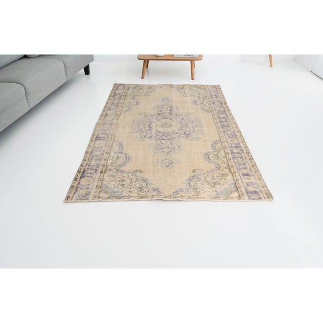 This is a vintage Turkish Oushak rug from the Mid 20th Century. The piece was hand-knotted.