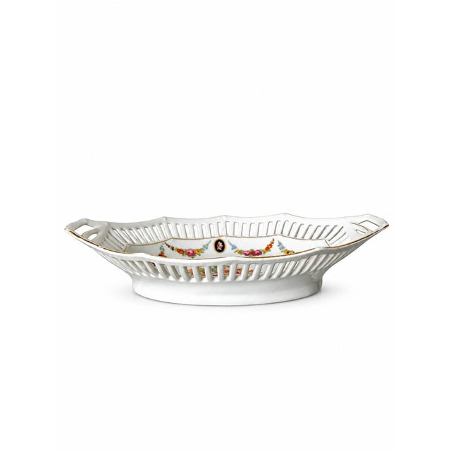 An elegant German porcelain tray with an elongated, faceted oval shape, two integrated handles and a delicate pierced...