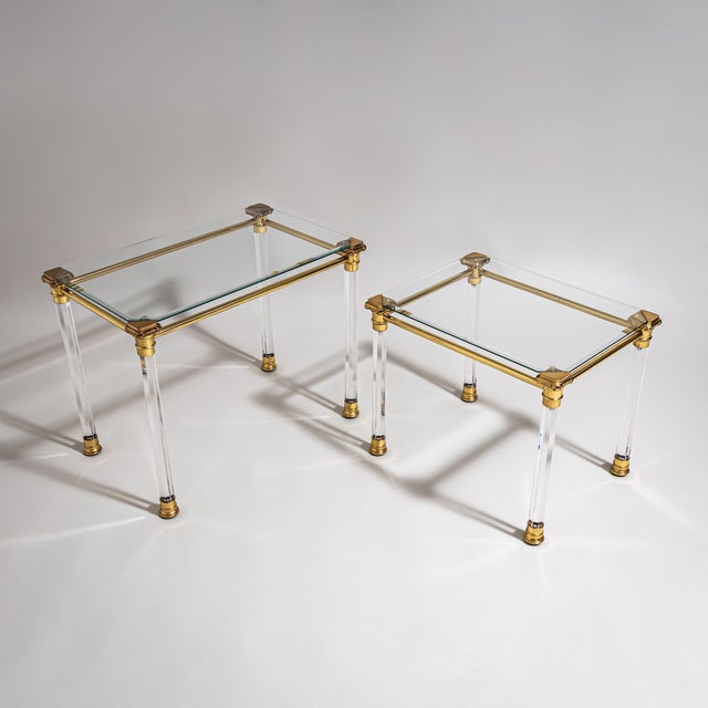 Two rectangular coffee tables with faceted column legs featuring stylized brass capitals and bases. The tabletops are...
