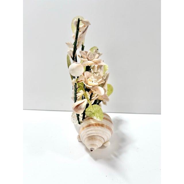 A charming vintage shell flower arrangement crafted from natural seashells and arranged in a large spiral conch shell...