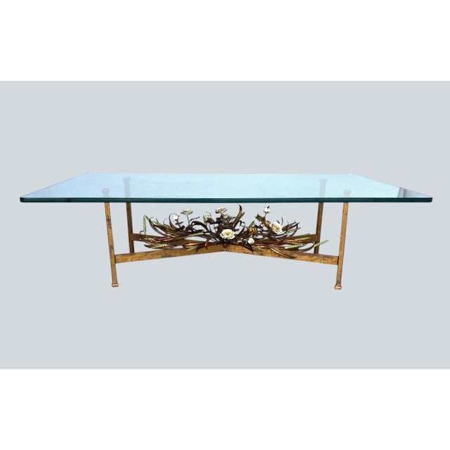 A glass-top Italian coffee table. The base is gold gilded with tole and pottery flowers and leaves.