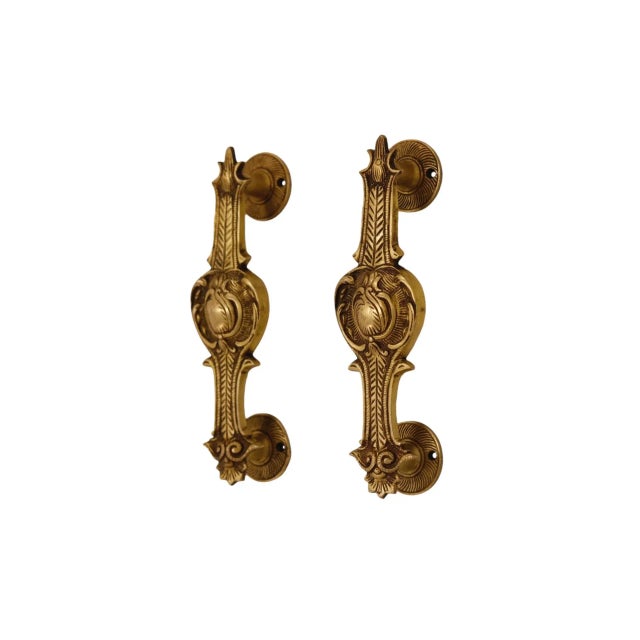 A pair of Indian brass bar door handles. Cast with a central floral medallion reminiscent of a poppy, with a chevron on...