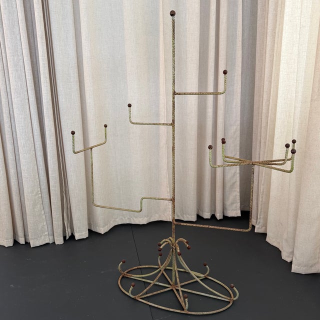 This mid-century millinery display stand showcases a striking, architectural silhouette crafted from slender braided metal...