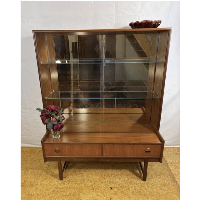 A stunning mid-century modern teak display cabinet by the renowned turnidge of london, dating from the 1960s–1970s....