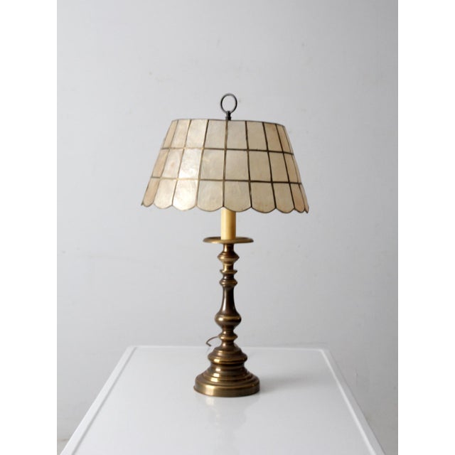 This vintage brass table lamp features a Capiz shell shade that casts a soft, ambient glow, bringing warmth and subtle...