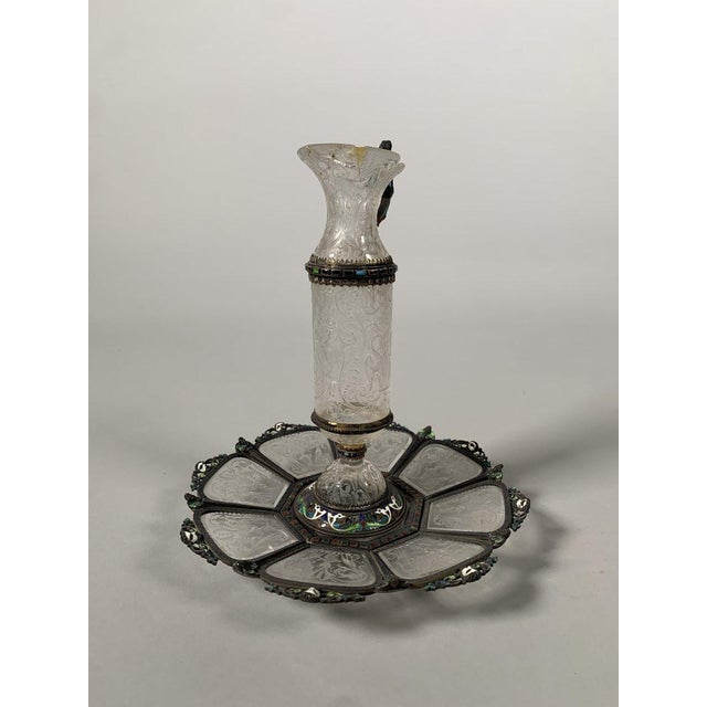 A finely engraved rock crystal ewer and stand with an enameled silver mount. Work in the Viennese Renaissance style of the...