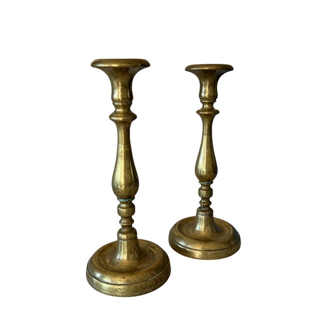 Pair of candlestick holders made of solid brass, likely hand-cast and lathe-turned, with beautiful patina. Each holder...