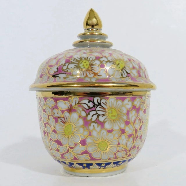 Small 1970s porcelain Thai benjarong jar with a cotton candy pink base. There are hand-painted white blossoms with yellow...