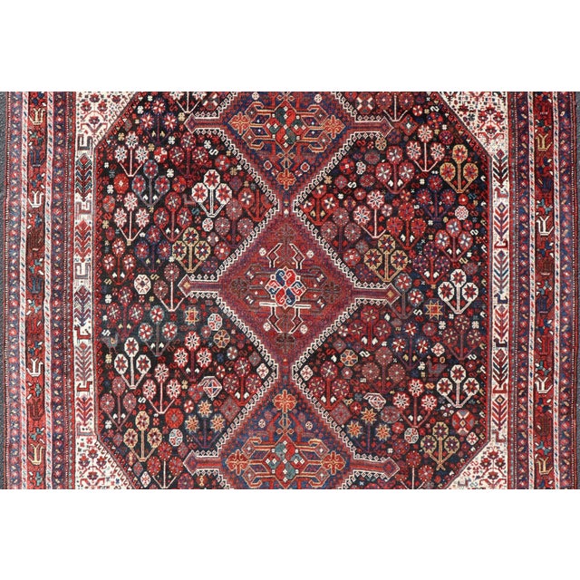This antique Persian Qashqai rug has been hand-knotted in wool and features an all-over sub-geometric design rendered in...