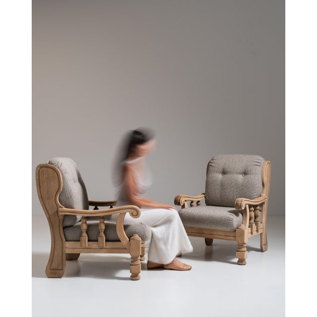 This pair of 1970s Brutalist oak upholstered armchairs from France, carved in blond oak with gray upholstered cushions....