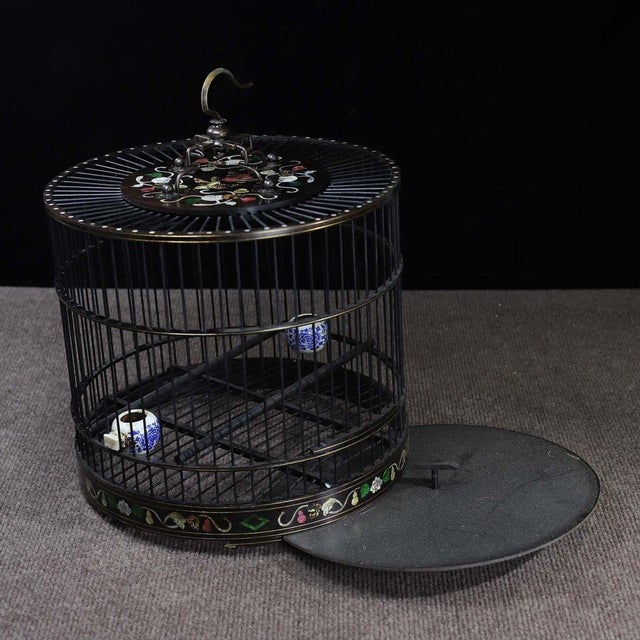 A beautifully crafted Chinese bird cage, likely made of black Zitan wood. The cage features a cylindrical form with...
