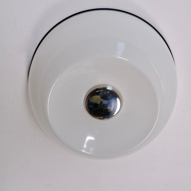 This minimalist and timeless wall lamp stands out for its glossy white plastic diffuser with a distinctive contrasting...