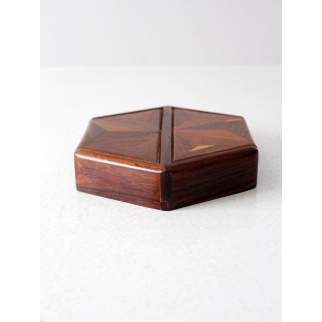 This mid-20th-century wooden parquetry box features a striking hexagonal shape and an intricate geometric double lid...
