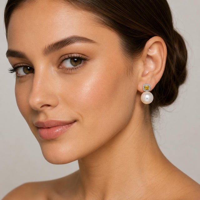 18k White gold earring with two 16mm South Sea Pearls and two natural yellow diamonds weighing 0.64 carats and round...