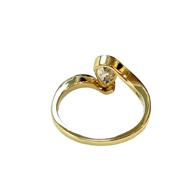 Elegant 18K yellow gold bypass ring featuring a 0.39 carat pear-cut diamond in a graceful, modern setting. Weight: 3.3g....