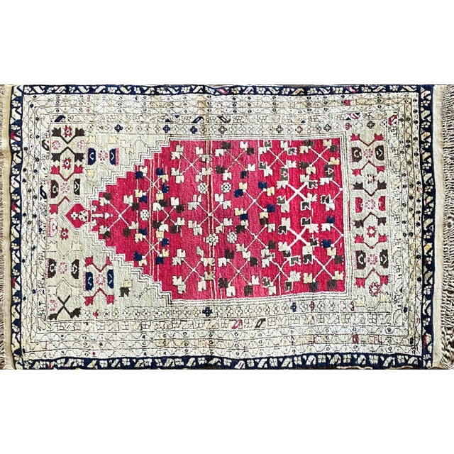 A beautiful and highly decorative antique Turkish prayer rug featuring a striking raspberry-red stepped mihrab set against...