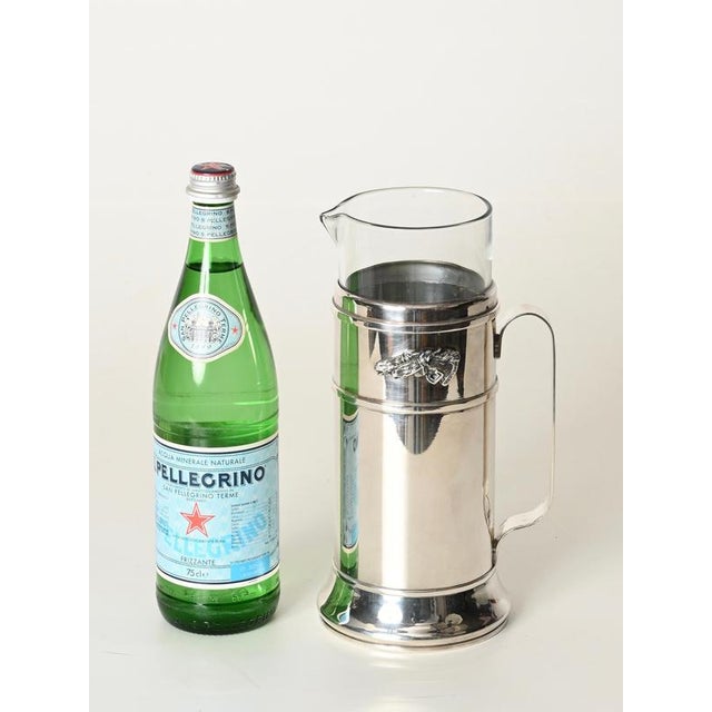 Marvelous and incredibly rare carafe in silver-plated metal and crystal glass, signed Gucci. This elegant sculptural piece...