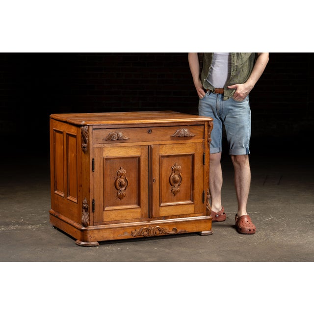 Antique carved oak cabinet with single drawer and double doors. Featuring a spacious interior with a single shelf, this...