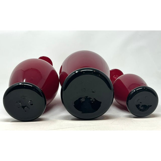 Donald Carlson Art Glass, Vase Trio American Artist A Trio of hand-blown cardinal red glass stick vases, each with applied...