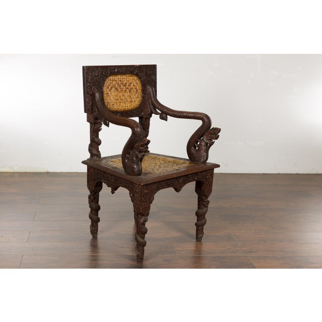 An Anglo-Indian carved wooden armchair from circa 1900 with carved back and mythical creatures on the arms. This...