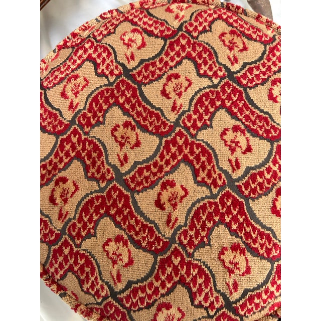 A handsome antique upholstered footstool featuring a circular form raised on turned wood legs. The stool is upholstered in...