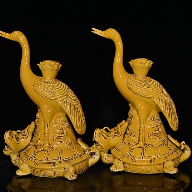 A striking pair of large Chinese yellow glazed porcelain candlesticks. Each piece features a tall, elegantly sculpted...